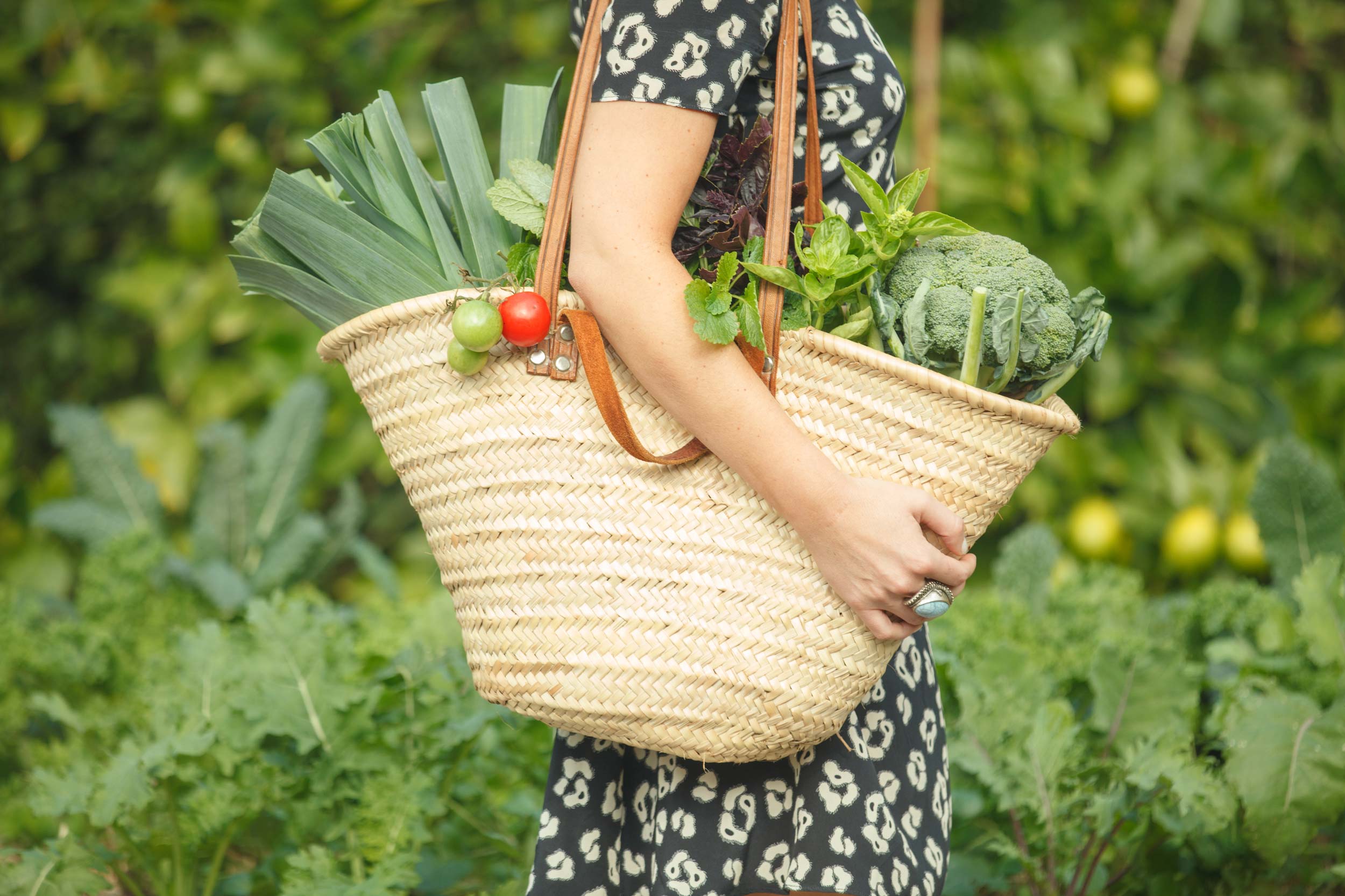 Woman holding a market bag full of organic produce.